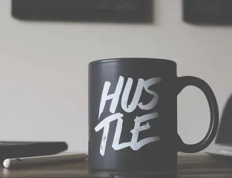 A black coffee mug with the world Hustle on it